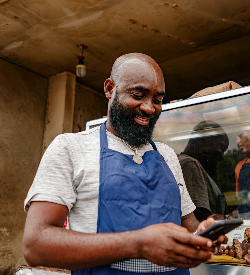 Comerciante sorrindo olhando o celular